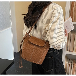 Rear view of a leopard print crossbody bucket bag on a model in a cozy library setting