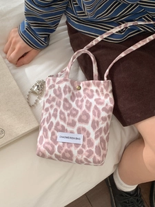 Pink leopard print canvas crossbody bag with top handle and heart charm detail