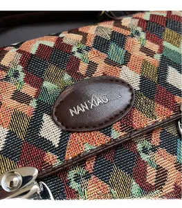 Detail of colorful jacquard woven texture with oval leather logo and silver metal clasp