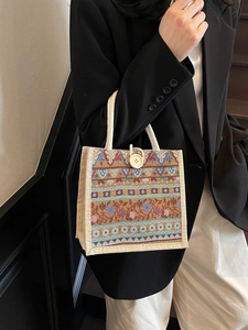 Beige bohemian woven tote bag with white rope handles and button closure held by model