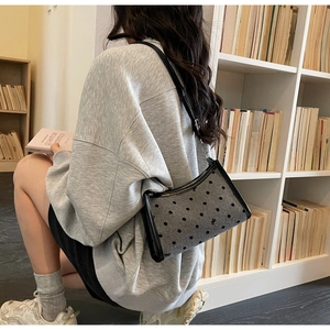Detail of grey polka dot underarm bag with bow embroidery and black leather trim