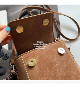 Detail view of brown PU leather bag showing dual magnetic snap closures and yellow stitching