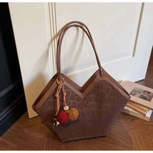 Detail of leopard print tote bag with soft texture and decorative pom-pom pendant