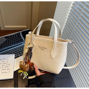 Close-up of cream white tote bag with bear charm and adjustable strap for women
