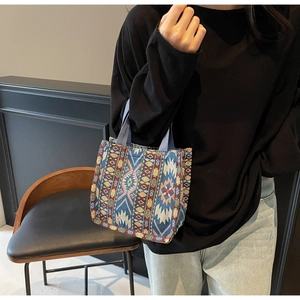 Detail of colorful ethnic woven tote bag featuring geometric patterns and blue handles