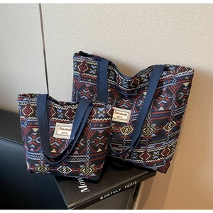 Detail of blue woven canvas bucket bag set with red geometric ethnic patterns