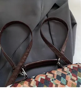 Detail of multi-color geometric woven bag featuring premium brown leather strap and silver D-ring