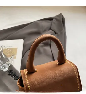 Detailed macro view of brown leather handbag handle and golden metal bead edge decor