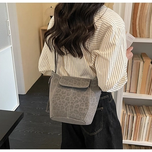 Close-up of leopard print suede bucket bag worn as a shoulder bag in a lifestyle setting