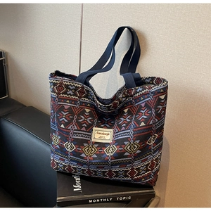 Detailed close-up of woven ethnic pattern tote bag on a black leather surface