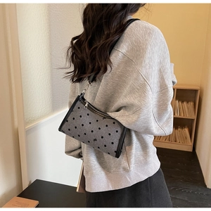 Detail of grey polka dot underarm bag with black bow and silver metallic zipper