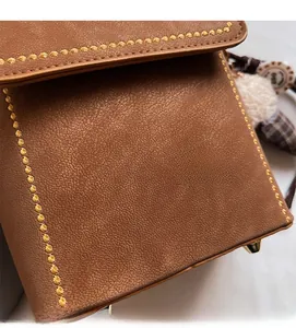 Close-up of brown litchi pattern leather bag with yellow stitching and gold metal studs