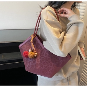 Detail view of burgundy leopard tote bag with soft suede texture and colorful pompom tassel
