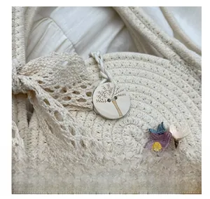 Detail showing the wooden button with tree engraving and floral accents on the woven bag
