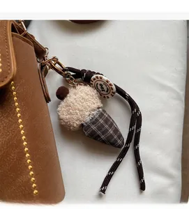 Close-up of plush ice cream bag charm with woven rope and round tag on leather bag