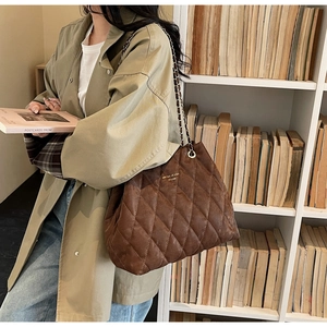 Detail of brown quilted tote bag with golden chain strap and retro leather texture