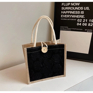 Detail of jute handbag with black floral jacquard, rope handle and wooden button