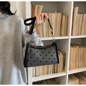 Detailed macro view of gray polka dot underarm bag with black bow and textile texture