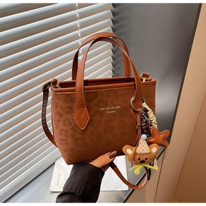 Detail of vintage leopard print tote bag with plush bear charm and leather strap