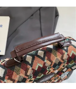 Detail of multi-color geometric woven fabric with brown leather handle and metal rings