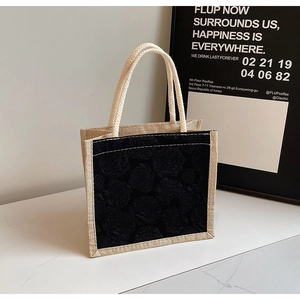 Detail of black rose embossed texture and woven trim on a small tote bag