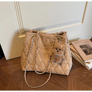 Detail of khaki quilted tote bag with chain strap and cute plush puppy charm