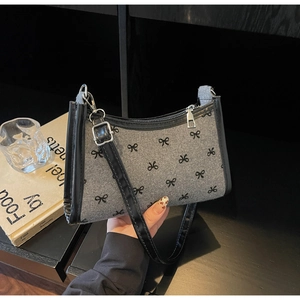 Close-up of grey wool underarm bag featuring black bow patterns and leather strap