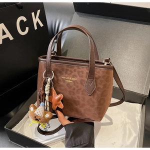 Detailed view of brown leopard print tote bag with plush bear charm in luxury gift box
