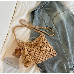 Close-up of handmade woven straw bag with floral pattern, tassels, and a zipper closure