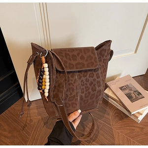 Detail of leopard print suede bucket bag with white stitching and wood bead charm