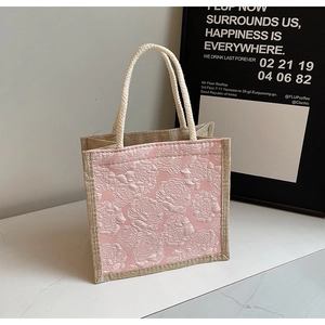 Detailed close-up of pink rose floral jacquard fabric and rustic jute material on the tote bag