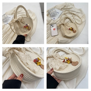 Detail of round straw bag with white lace bow, colorful floral charms and wood button