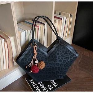 Detail of leopard print tote bag with V-shaped opening and decorative beaded tassel charm