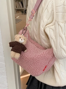 Sac bandoulière en peluche rose avec breloque ours, porté sur pull blanc torsadé