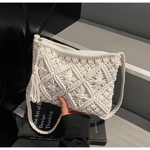 Detail shot of bohemian handmade macramé straw bag with tassel fringe and zip closure