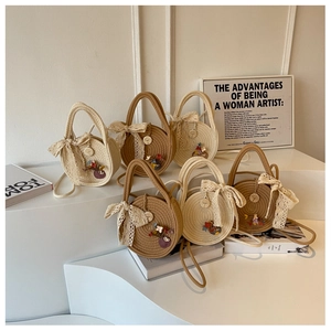 Detail of round straw handbags with lace bows and shoulder straps on white steps