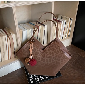 Detail of leopard print tote bag with brown suede finish and stylish plush ball charm
