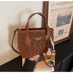 Detail of leopard print tote bag with brown faux suede texture and cute bear charm