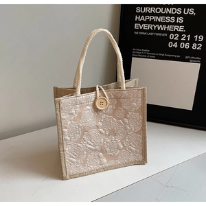 Detail of linen handbag with jacquard rose pattern and round wooden button closure