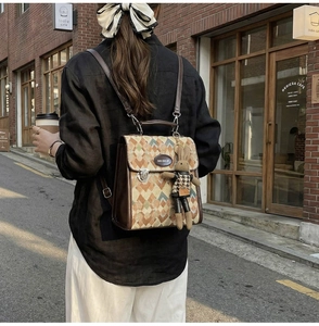 Detail of diamond lattice pattern backpack with brown leather trim and cute rabbit charm