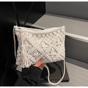 Detail of white handmade macrame bag featuring geometric weaving and fringe accents