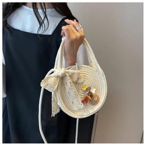 Detail of round straw bag with lace bow, floral charm and heart leather patch accent