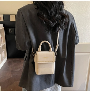 Detail showing cream leather mini crossbody bag with gold chain trim on a model