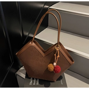 Close-up of brown suede tote bag with V-shaped opening and decorative plush charm