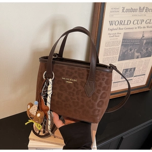 Detail of leopard embossed texture on retro brown tote bag with cute bear charm