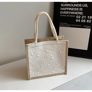 Close-up of rose embossed texture and woven rope handle on natural linen tote bag