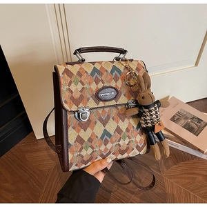 Detail of multi-color quilted fabric backpack with leather trim and rabbit charm