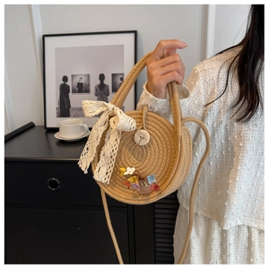 Detail of round straw bag featuring white lace bow, 3D floral embroidery and wood button
