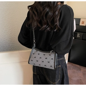 Detail of grey felt shoulder bag with black embroidered bows and silver zipper detail