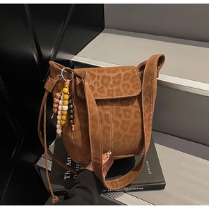 Detail of leopard print bucket bag with beaded tassel charm on a dark artistic background